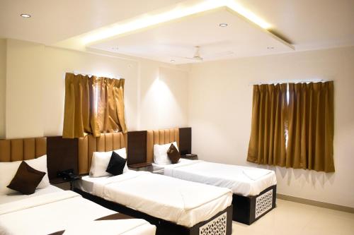 a room with three beds and curtains in it at Lotus Excutive in Pune