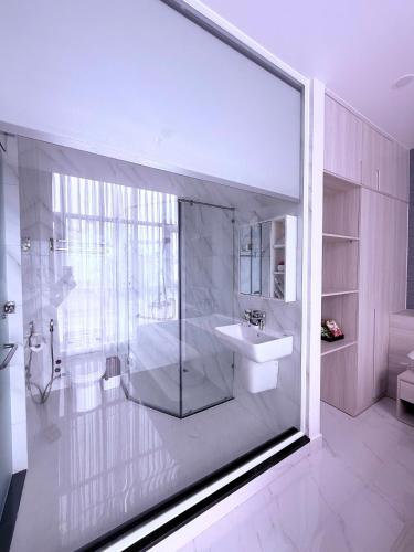 a white bathroom with a sink and a shower at The Luxury Hotel in Ho Chi Minh City
