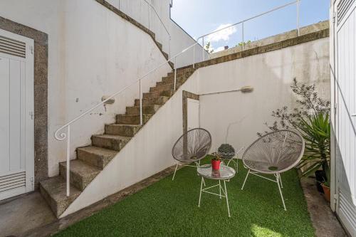 a patio with two chairs and a table and stairs at GuestReady - Charming House Marquês in Porto