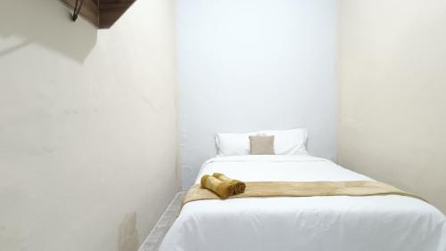 a white bed with a towel on top of it at Omah Sewu Sakura By Reccoma in Surabaya