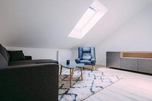 Una sala de estar con un sofá, una silla y una mesa. en Apartament ,,Loft pod piórem", en Nowy Sącz