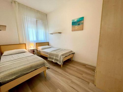 a small room with two beds and a window at Terraced house with private garden in Porto Santa Margherita di Caorle