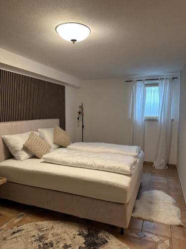 a bedroom with a large bed with white sheets and a window at Auhäusl Residence for 6 with private Sauna by Belle-Stay in Reith bei Kitzbühel