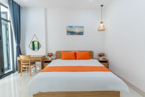 a bedroom with a bed with orange pillows and a table at Sunny Beach Villa in Danang