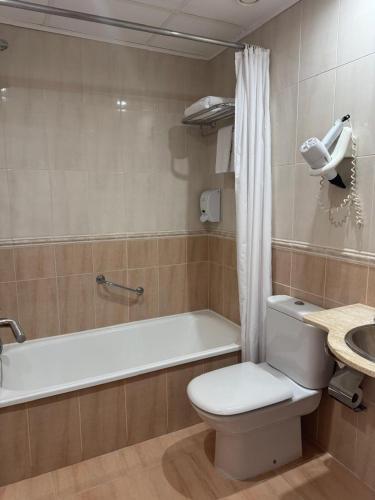 a bathroom with a toilet and a tub and a sink at Hotel Plaza Inn in Figueres