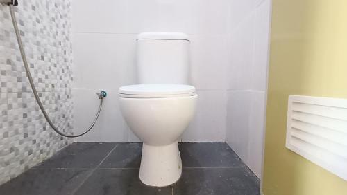 a white toilet in a bathroom with a shower at Omah Sewu Sakura By Reccoma in Surabaya