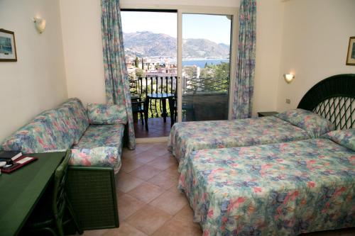 een hotelkamer met een bank en een stoel en een bank en een raam bij Hotel Villa Bianca Resort in Taormina