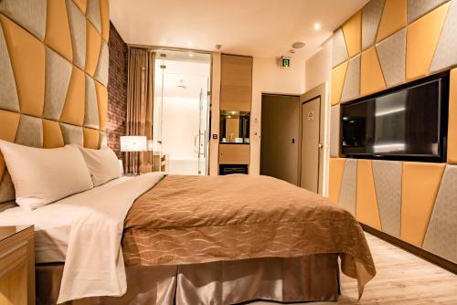 a bedroom with a bed and a flat screen tv at Eusta Motel in Taichung