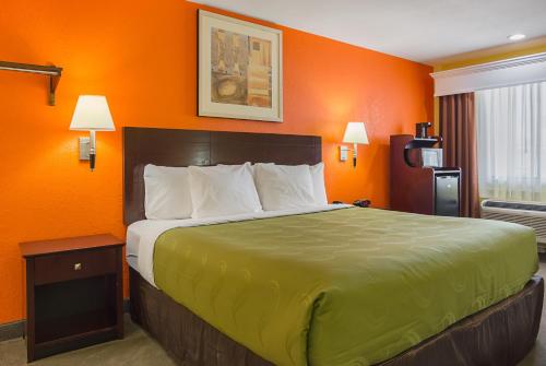 a bed in a hotel room with orange walls at Quality Inn Carthage in Carthage