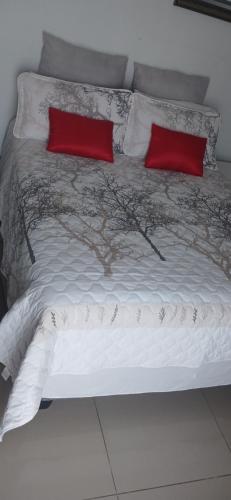 a white bed with two red pillows on it at Blessing in East London