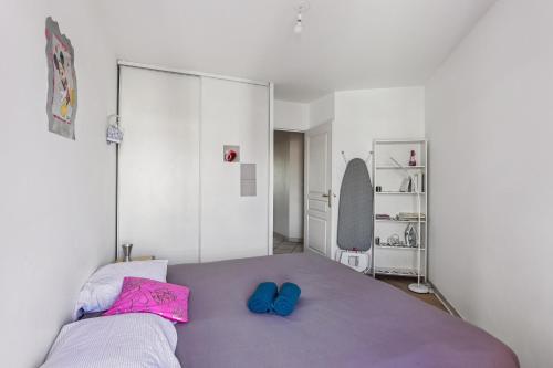 a bedroom with a purple bed with two blue slippers at Superbe T3 Villeurbanne Centre avec climatisation in Villeurbanne