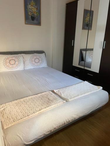 a bedroom with a bed with white sheets and a mirror at VEZO Apartment in Skopje