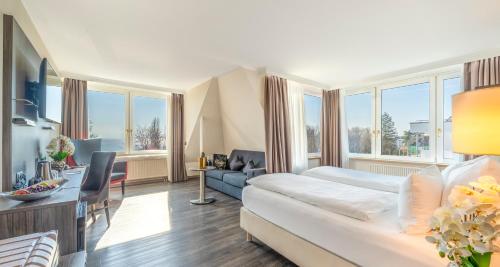 a living room with a white couch in a room with windows at PLAZA Hotel Buchhorner Hof in Friedrichshafen
