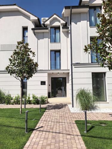 a white house with a brick path in front of it at Royal Rooms by J'adore in Lugoj
