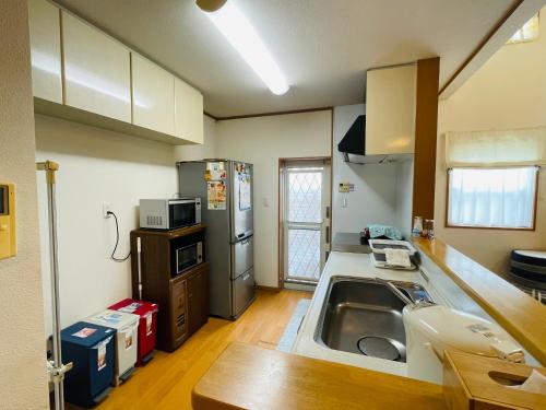 a kitchen with a sink and a refrigerator at GuestHouse MISAKI 一棟貸切駐車場2台最寄駅はJR石山駅瀬田南郷ゴルフ場近し琵琶湖京都宇治奈良大阪の観光は便利です in Otsu