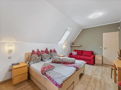 a bedroom with a bed and a red couch at Apartment Na mechu-2 by Interhome in Mezná
