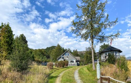a house in the middle of a field with a tree at Stunning Home In Korssund With Wifi in Våge