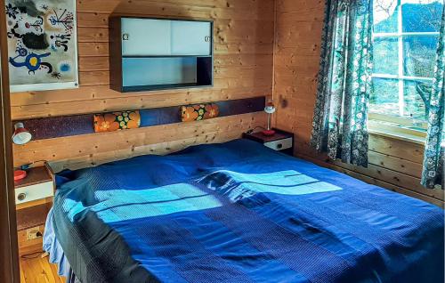 a bedroom with a blue bed in a wooden room at Stunning Home In Korssund With Wifi in Våge