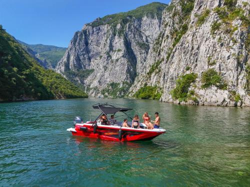 a group of people on a red boat in the water at Bujtina Adora in Ara të Lumit