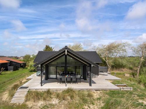 a black house with a deck and a table at Holiday Home Gubbe - 500m from the sea by Interhome in Lakolk