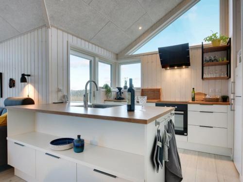 a kitchen with white cabinets and a large window at Holiday Home Gubbe - 500m from the sea by Interhome in Lakolk