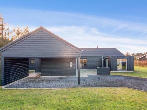 una casa con techo negro y patio en Holiday Home Øthbiorn - 1-1km from the sea by Interhome, en Løkken