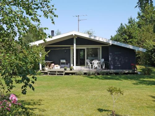 a black house with a garden and a lawn at Holiday Home Menard - 400m from the sea by Interhome in Ørsted