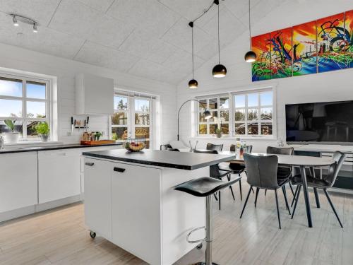 a kitchen with white cabinets and a table and chairs at Holiday Home Gizella - 500m to the inlet by Interhome in Spottrup