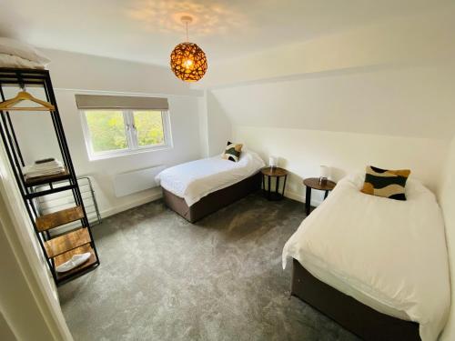 a bedroom with two beds and a chandelier at 2 bedroom cottage in Bromley suitable for 4 people in Bickley