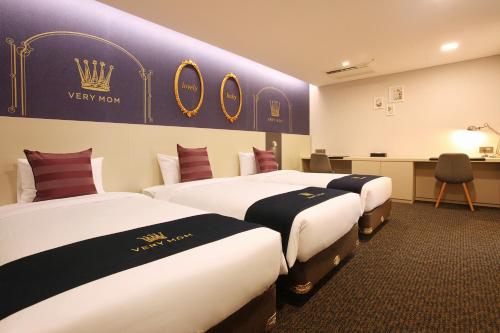 two beds in a hotel room with a sign on the wall at Hotel Skypark Kingstown Dongdaemun in Seoul