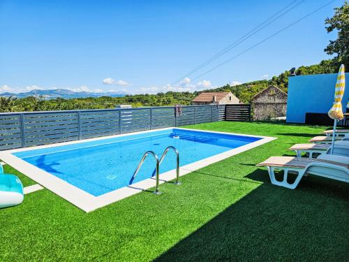 a swimming pool on a lawn with chairs next to it at Holiday Home Sunrise by Interhome in Janjina