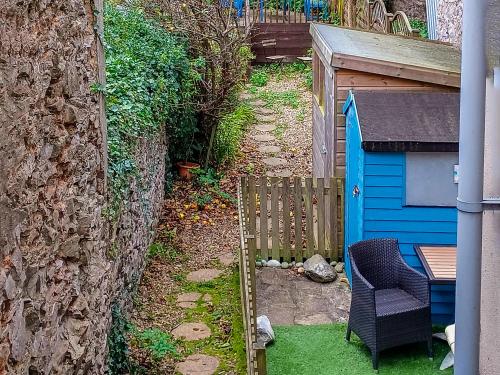 a small garden with a blue shed and a chair at Rockhopper Cottage in Brixham
