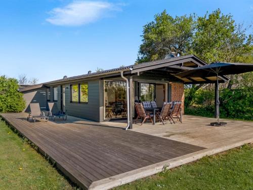 a deck with chairs and an umbrella on a house at Holiday Home Ørn - 5m from the sea by Interhome in Binderup Strand