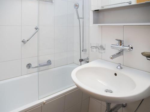 a white bathroom with a sink and a shower at Apartment La Siala Apt-56A by Interhome in Falera
