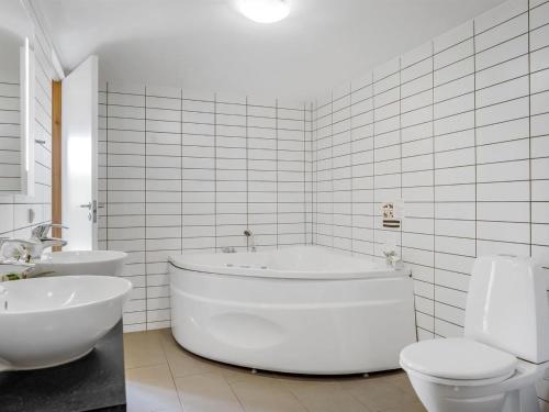a white bathroom with a tub and two toilets at Holiday Home Ginne - 1km to the fjord by Interhome in Løgstør