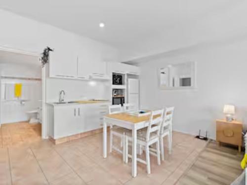 a kitchen with white cabinets and a table and chairs at Classic Coastal Beachfront, Surfers Paradise-Pool in Gold Coast