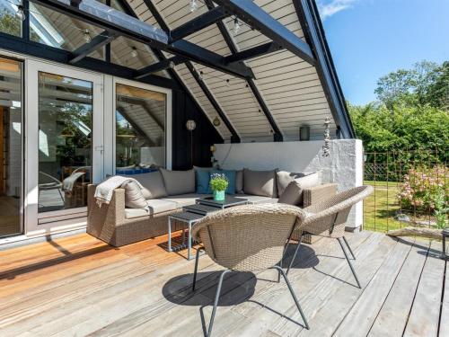 a patio with a couch and chairs on a wooden deck at Holiday Home Frodde - 200m from the sea by Interhome in Østerby