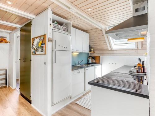 a kitchen with white cabinets and a refrigerator at Holiday Home Frodde - 200m from the sea by Interhome in Østerby