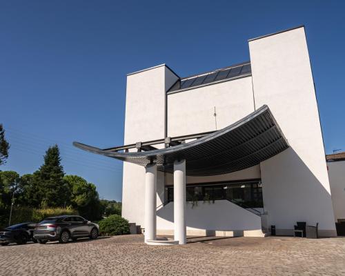 a white building with a car parked in front of it at Hotel Giada Viale del Sole in Vicenza