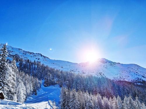 a mountain covered in snow with the sun shining on it at Apartment Bellentre Chalet le Pommier 5 by Interhome in Bellentre