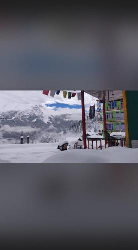 a bench in the snow with a view of a mountain at Iris cafe and cozy stay in Tosh