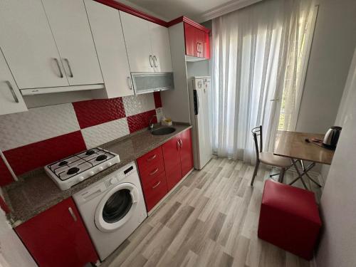 a small kitchen with red cabinets and a washing machine at İzmir homes in Buca