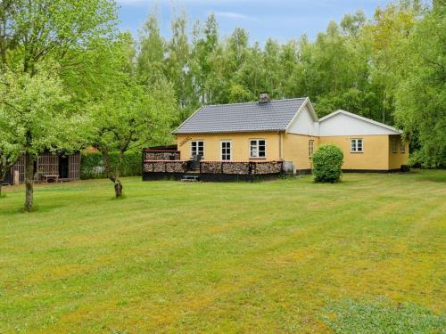 a yellow house in the middle of a yard at Holiday Home Andri - 1-5km from the sea by Interhome in Rønne