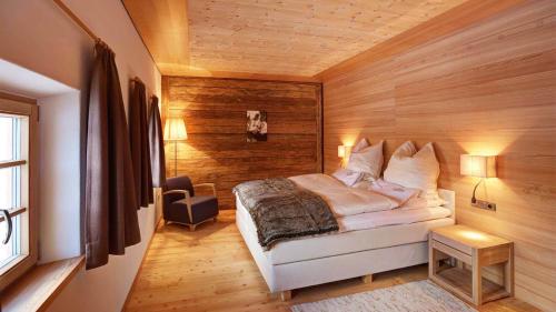 a bedroom with a bed and a wooden wall at Silentium Dolomites Chalet in Monguelfo