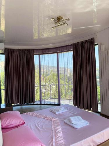 a bedroom with a large bed with a large window at Shato mash in Tbilisi City