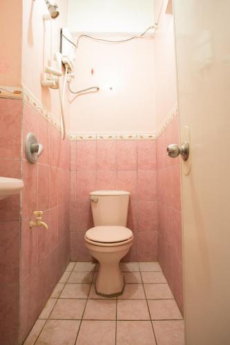 a bathroom with a toilet in a pink tiled bathroom at GV Hotel - Masbate in Masbate