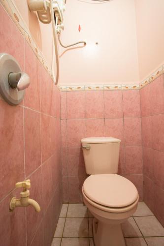 a bathroom with a white toilet in a pink bathroom at GV Hotel - Masbate in Masbate