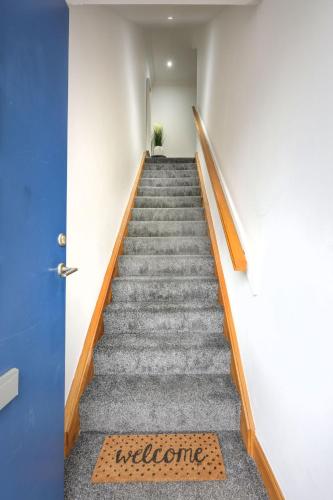 a staircase with a blue door and a welcome mat at Apartment Forres View by Interhome in Forres
