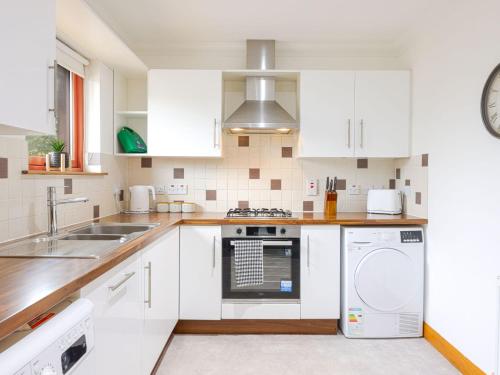 a kitchen with white cabinets and a washer and dryer at Apartment Forres View by Interhome in Forres