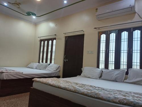 two beds in a room with windows at Kanha Guest House in Varanasi
